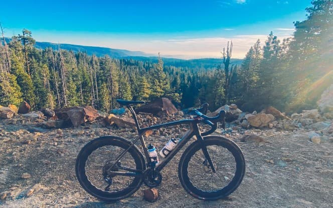 Black road bike overlooking a forested mountain valley